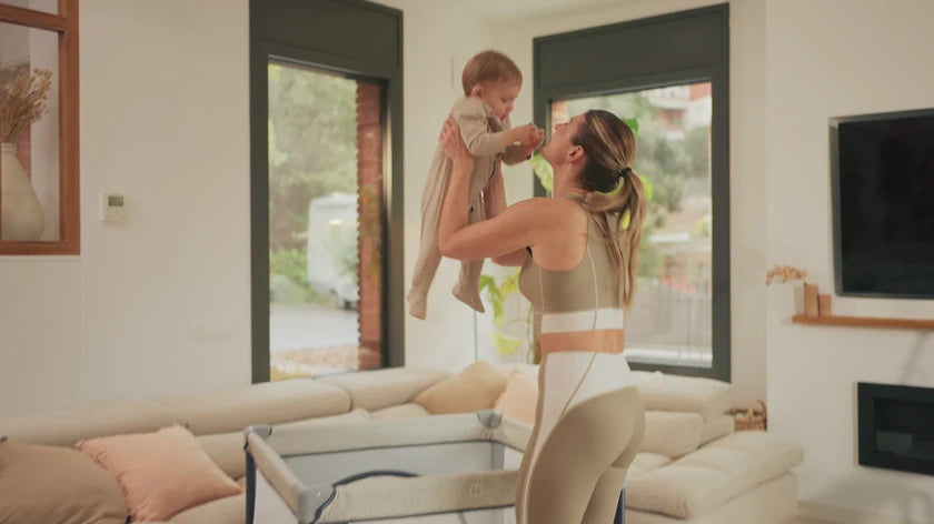 A mother holding her baby by the window at home