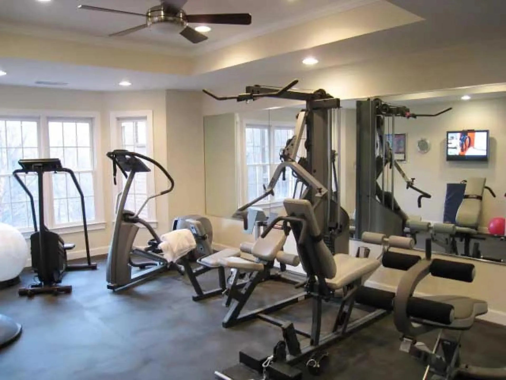 Gym interior with various exercise machines and a television on the wall.