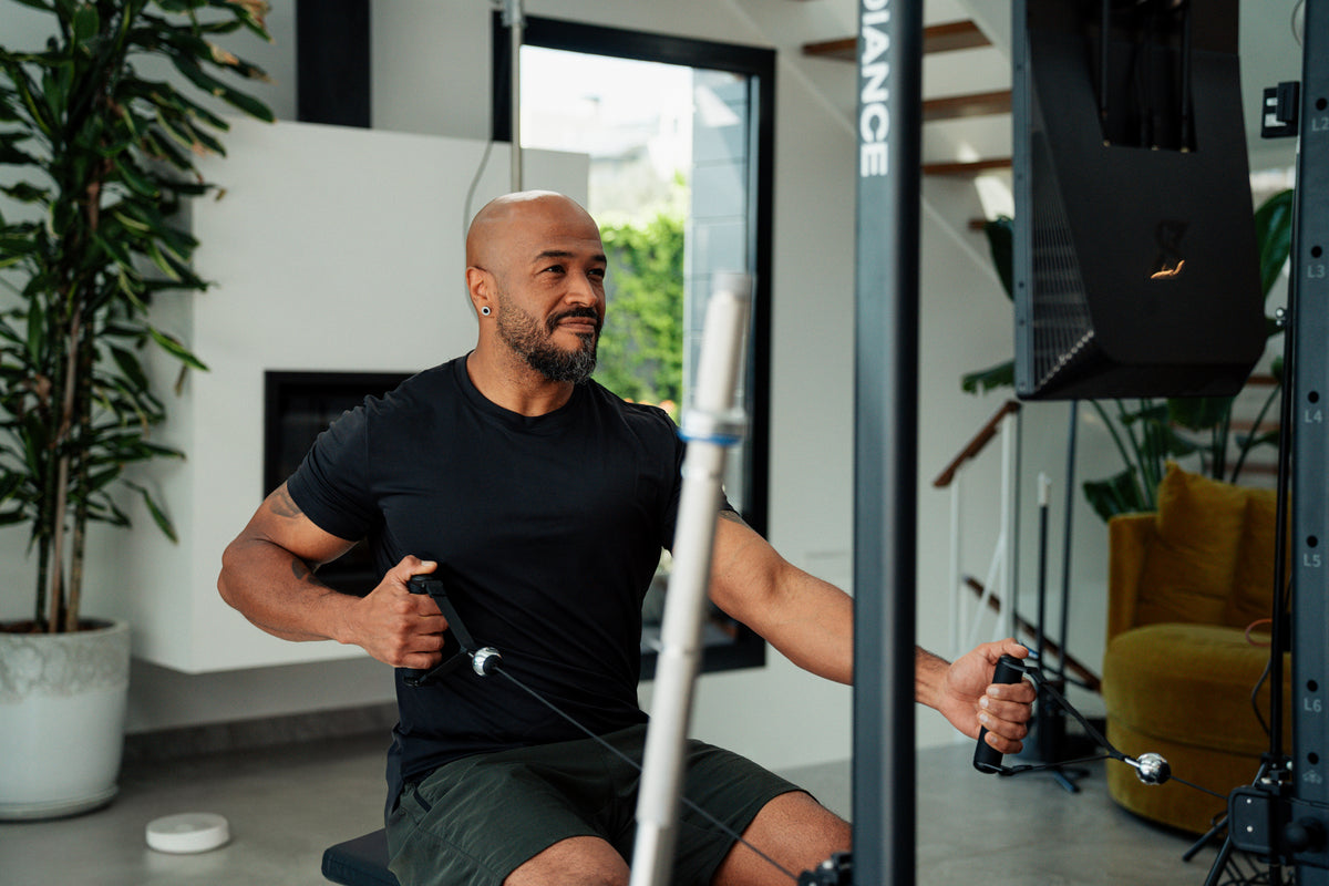 Man exercising on a cable machine in a home gym setting