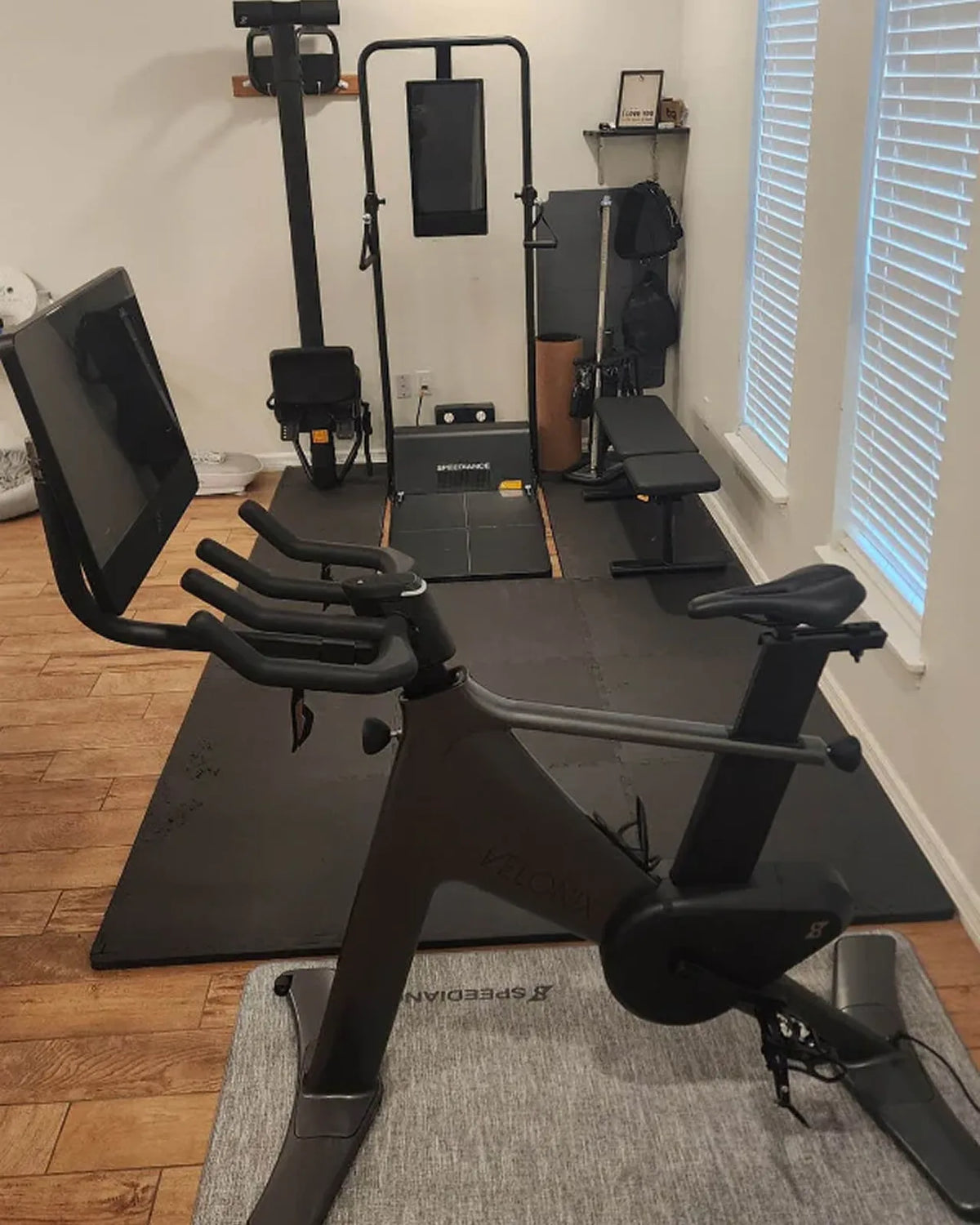 Home gym setup with exercise equipment on a wooden floor.