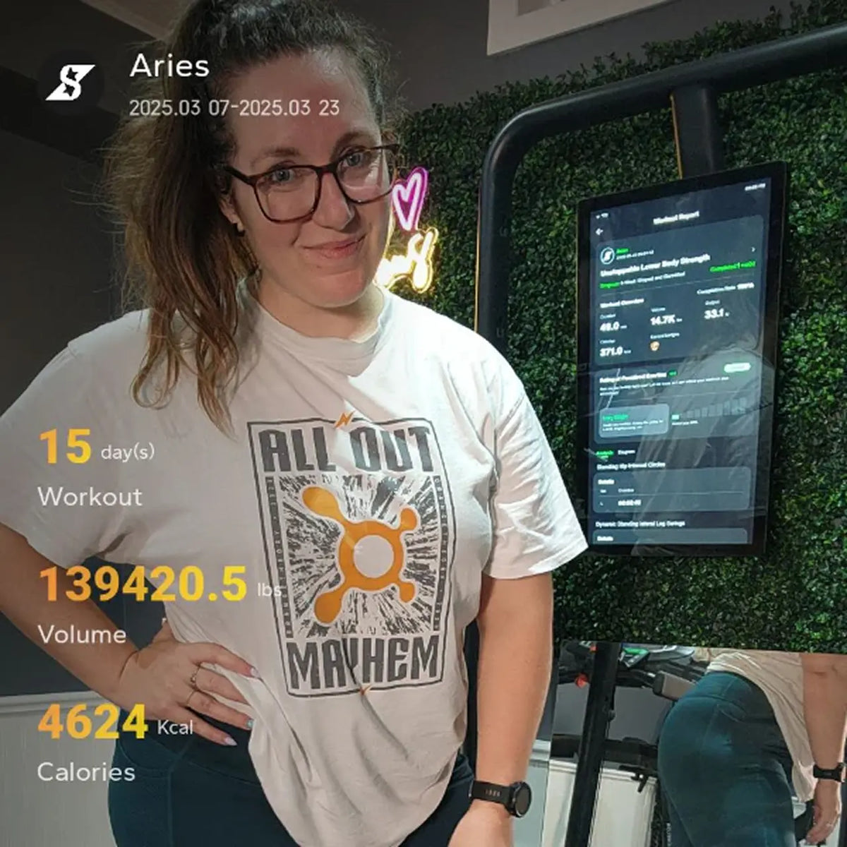 Person wearing a white t-shirt with graphic design, standing in front of a digital display.