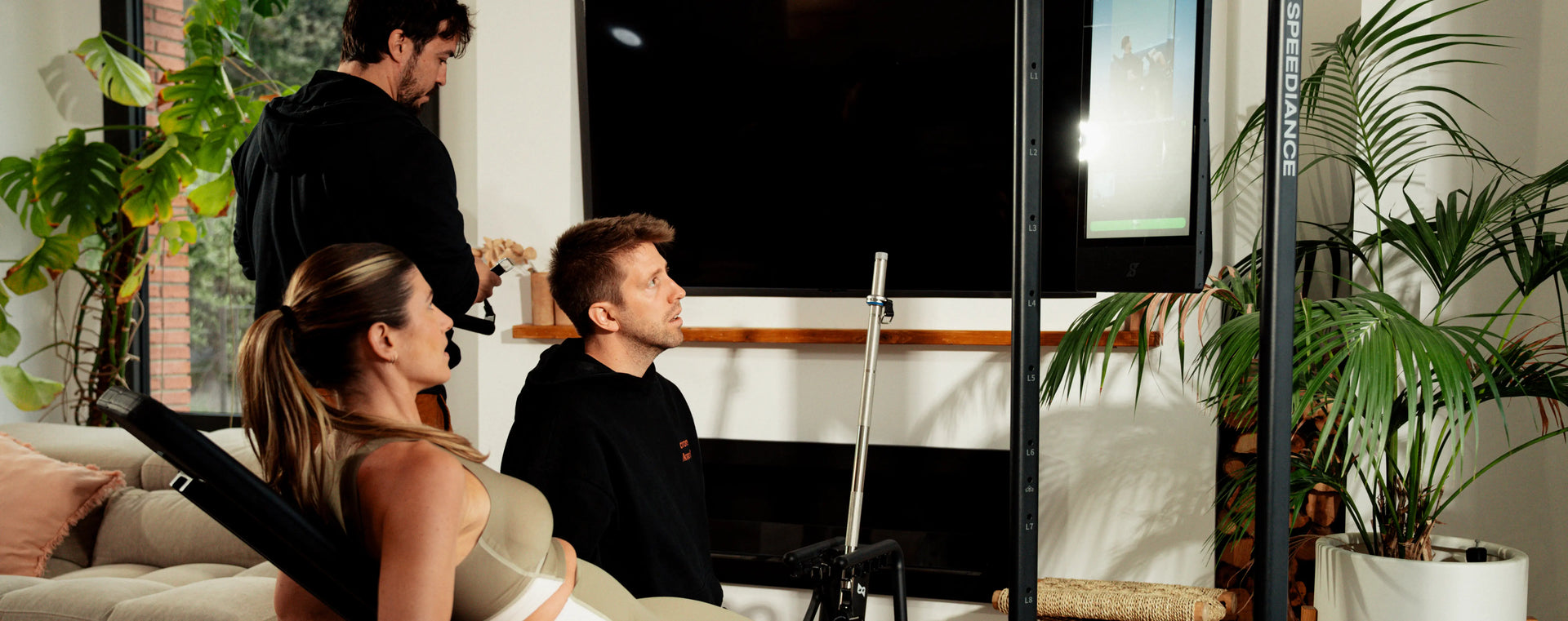 Two men and a woman in a modern living room with large windows.