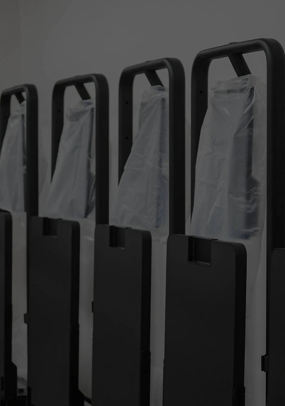 Row of black suitcases with clear plastic bags on a dark background