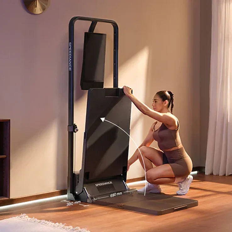 Woman using a home gym machine in a room with neutral walls and wooden floor.
